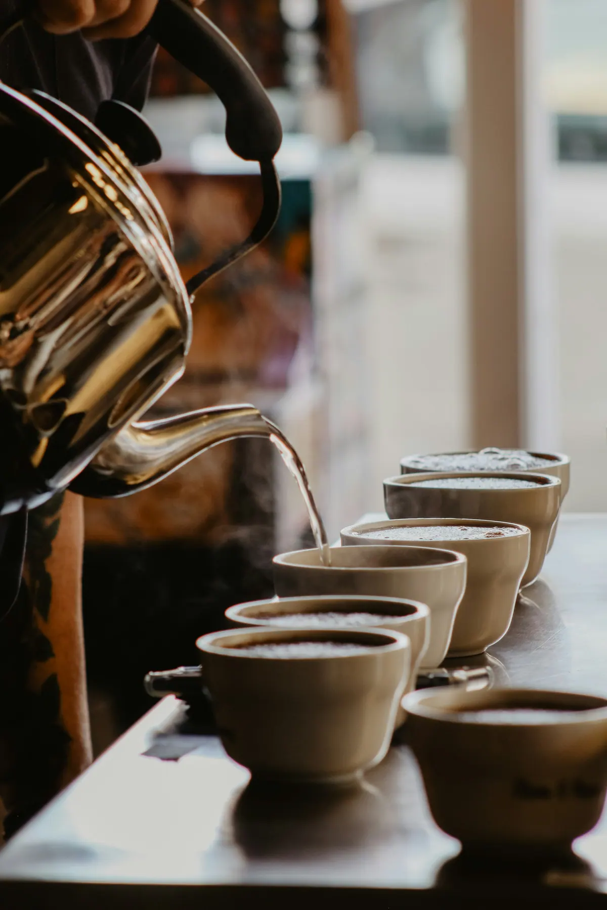 Hot water poured from a kettle into a row of cupping bowls