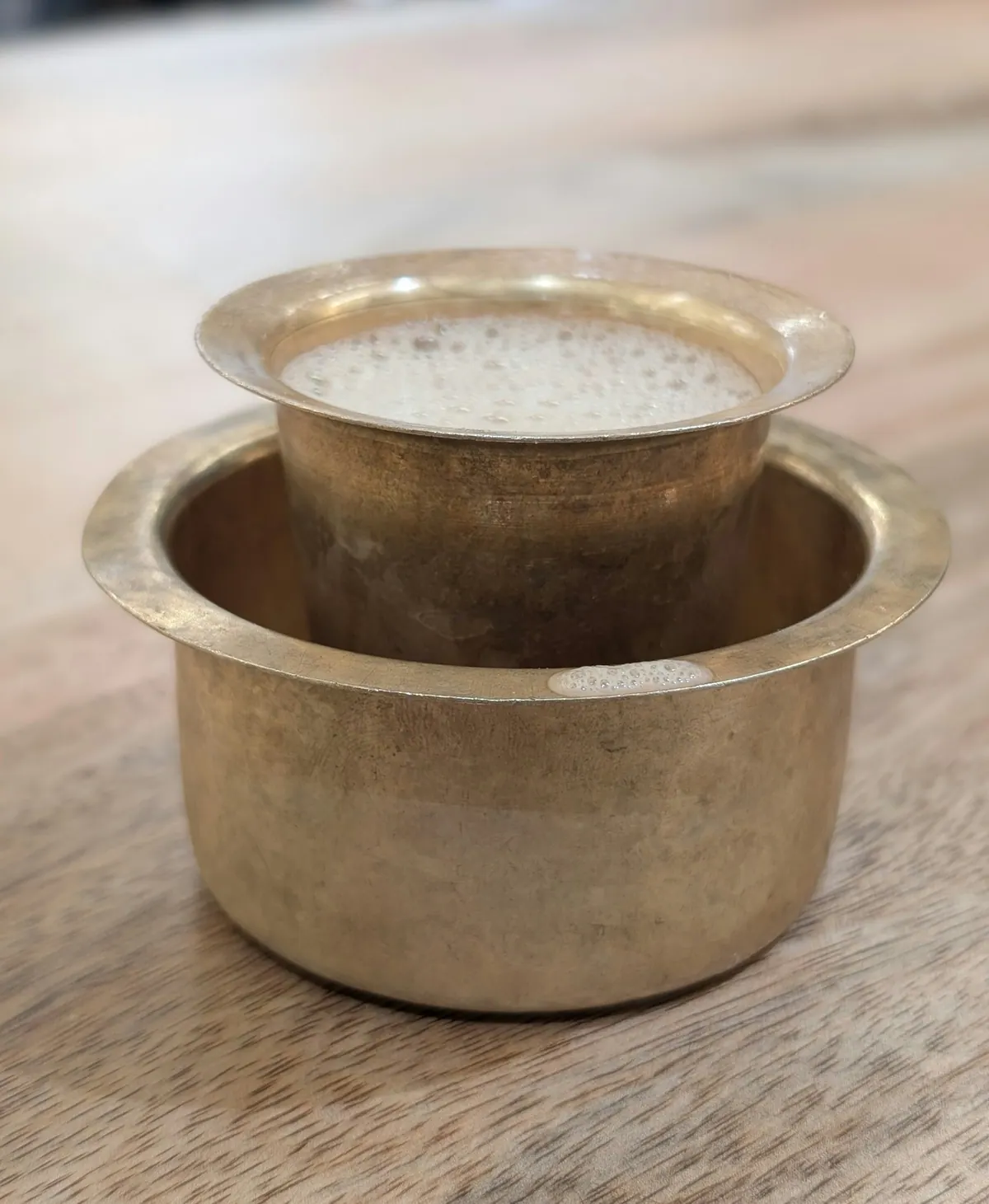 Frothy South Indian filter coffee in a brass tumbler and davara