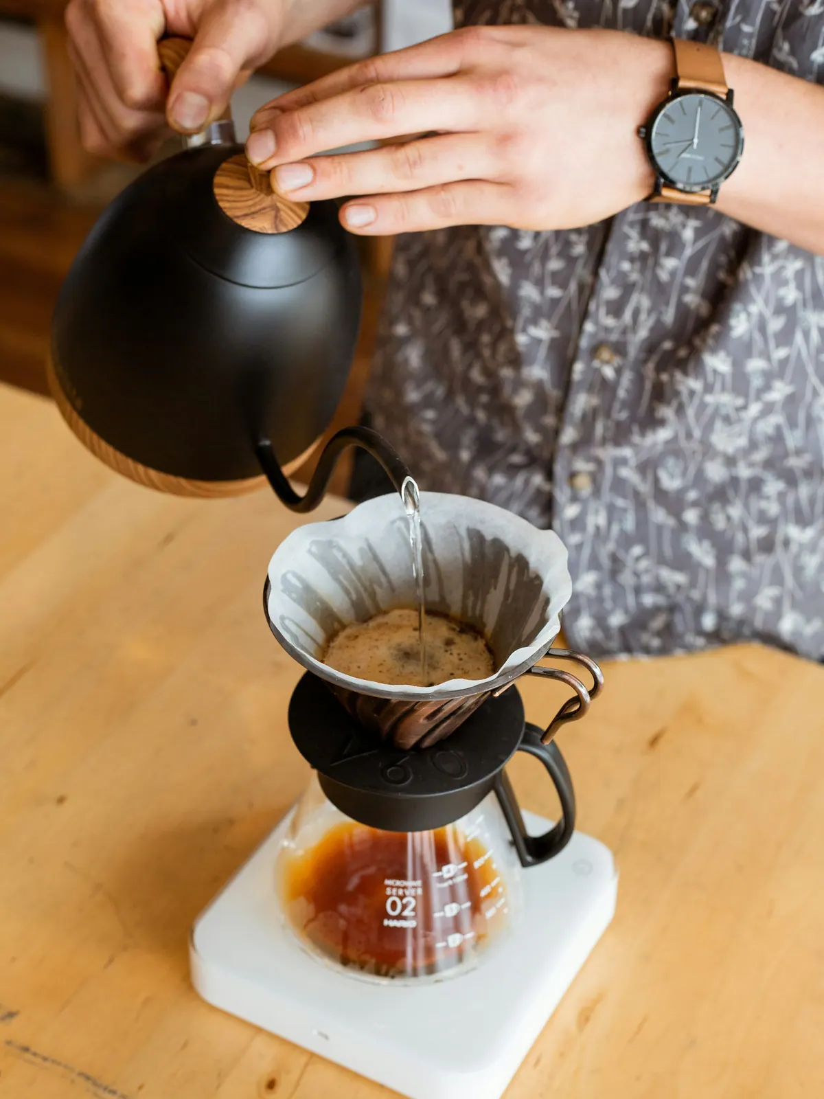 Water poured from a gooseneck kettle into a pour-over dripper on a scale